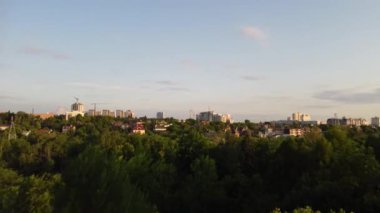 Aerial evening view from fpv drone on green summer Kharkiv city center district near recreation park Sarzhyn Yar. Residential area buildings in sunset light