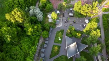 Aerial sunset look down fpv view on water spring in green summer Kharkiv city center popular recreation park Sarzhyn Yar. Botanical garden with water spring and playground