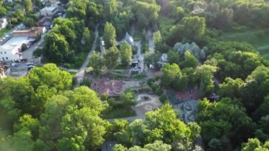 Aerial evening tilt-down view on water spring in green summer Kharkiv city center recreation park Sarzhyn Yar. Botanical garden with water spring and playground