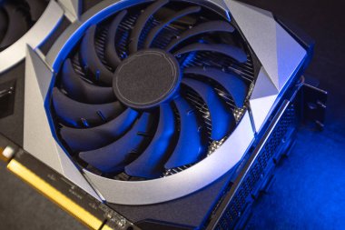 Gpu graphics card fan top view. Cooler fan close-up in bright blue light on black, PC hardware details. Components from computer cooling system with selective focus
