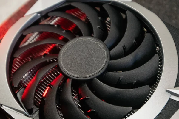 Cooler fan on Gpu graphics video card, close-up in red light with selective focus, PC hardware details. Components from computer for gaming or crypto mining