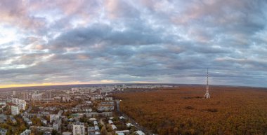 Günbatımının sonbahar şehri manzarası. Telekomünikasyon kulesi, yerleşim bölgesi yakınlarında, gökyüzü bulutlu. Kharkiv, Ukrayna