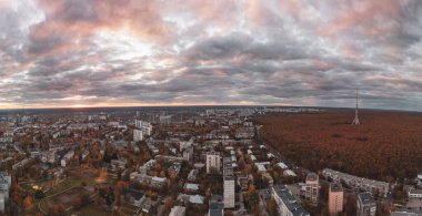 Günbatımının sonbahar şehri manzarası. Telekomünikasyon kulesi, yerleşim bölgesi yakınlarındaki renkli bir ormanda. Manzaralı bulutlar. Kharkiv, Ukrayna