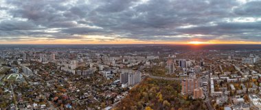 Gökyüzü canlı sonbahar şehri parkı günbatımı manzaralı destansı bulutlar. İkametgah binaları ve gece ışığında giden arabalar. Kharkiv, Ukrayna