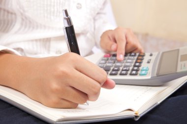 iş kadını onun not defterinde yazıyor ve Hesap makinesinde dikkate alır