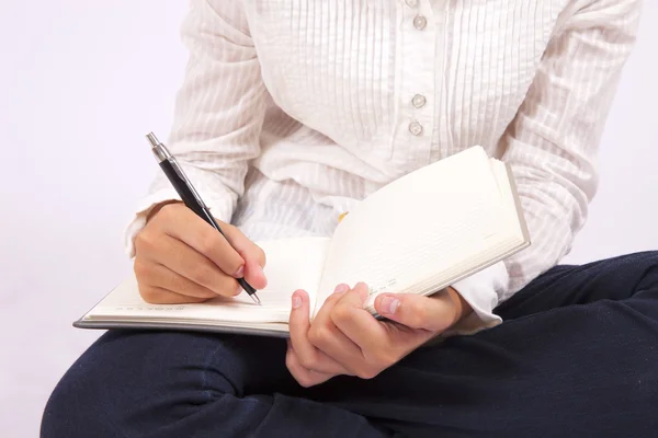 Zakenvrouw schrijft in haar notitieboekje — Stockfoto