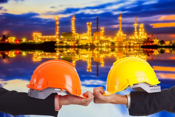Construction engineers with yellow and red hard hat on a background of a large plant — Stock Photo, Image