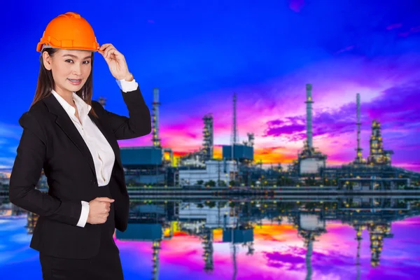 Engenheira feminina de pé em um capacete vermelho em um fundo de uma refinaria de petróleo — Fotografia de Stock