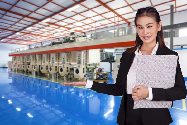 Businesswoman holding a folder with documents and stands inside the factory — Stock Photo, Image