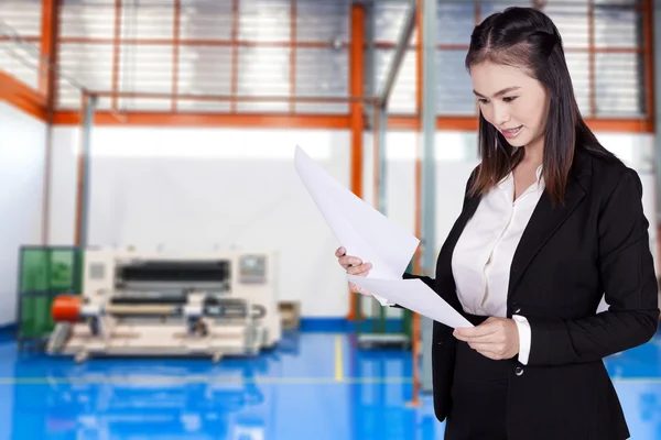Businesswoman reviewing documents inside the factory — Stock Photo, Image