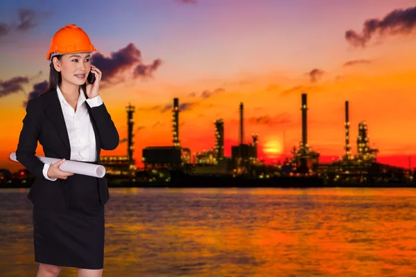 Female engineer holding a large project plan and talking on the phone — Stock Photo, Image