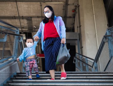 Coronavirus hastalığının resmi adı COVID-19 olan Coronavirus virüsünü önlemek için annesi ve Asyalı çocuk beyaz maske takıyor. .