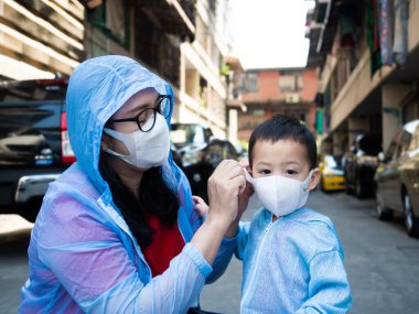 Coronavirus hastalığının resmi adı COVID-19 olan Coronavirus virüsünü önlemek için annesi ve Asyalı çocuk beyaz maske takıyor. .