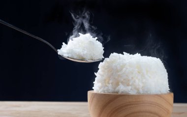 Koyu arkaplanda sıcak buharlı beyaz pilav, yemeye hazır.