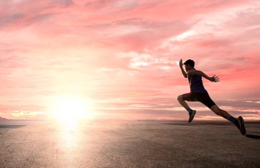 Yüksek hızlı koşan bir atlet olarak gün doğumuna doğru parlak gökyüzü arka grubuyla koşuyor.