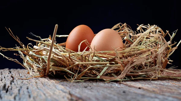 fresh eggs on wooden box with straw on wooden texture background in the night