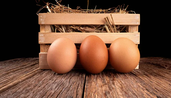 fresh eggs on wooden box with straw on wooden texture background in the night