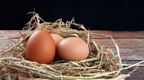 fresh eggs on wooden box with straw on wooden texture background in the night