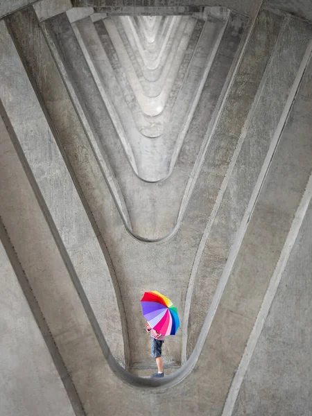男人用心灵感应透镜在多混凝土柱抽象图案背景下给儿子戴上彩色雨伞 — 图库照片