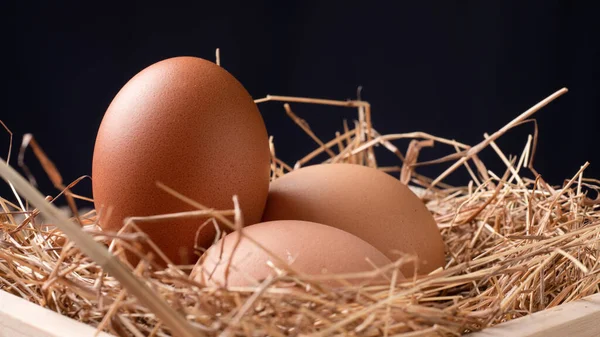 fresh eggs on wooden box with straw on wooden texture background in the night