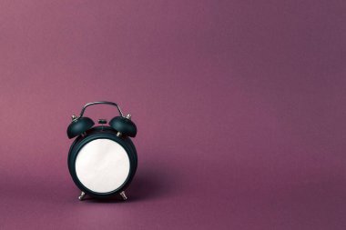 Mor bir arka planda geçmişe dönük siyah çalar saat. Boş beyaz arama.