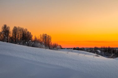 A beautiful view of the hills with trees on top against an orange sky. Travel concept