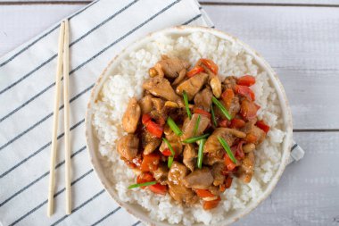 Kung Pao tavuğu yakınında peçete ile ahşap arka plan üzerinde beyaz plaka