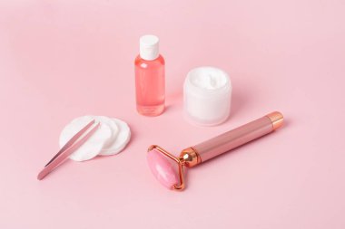 Gua Sha masaj aleti ve arka planda yüz silindiri. Yüz bakımı için masaj aleti, SPA güzellik tedavisi konsepti. Yüz bakımı için kozmetik, yüz masajı için silindir.