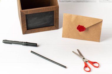 Beyaz ahşap arka planda bej bir zarf. Düğün davetiyesi, bayram, doğum günü, parti davetiyesi, beyaz masa damgalı zarf.