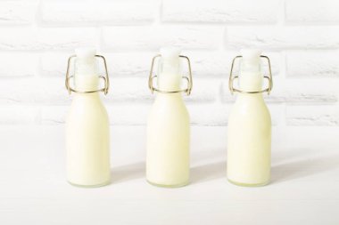 Beyaz üzerine izole edilmiş bir şişe süt. Sağlıklı yiyecekler. Ev yapımı kefir, ayran ya da probiyotik içeren yoğurt. Beyaz ahşap arka planda cam bir şişede yoğurt.