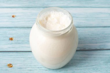 Süt kreması mavi bir masada cam bir kavanozda.