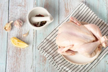 Fresh raw chicken on a plate and spices for cooking.