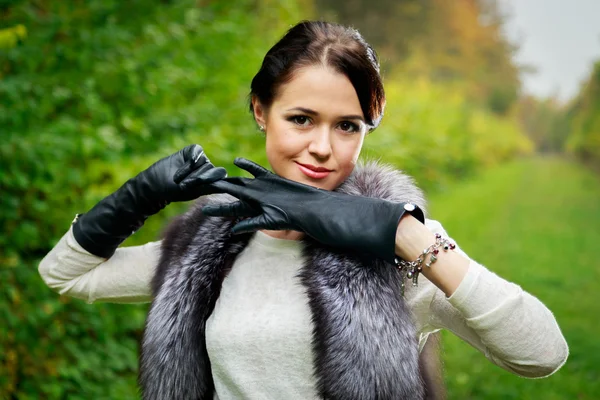 Mooi meisje in een rode rok en een bont vest in het forest — Stockfoto