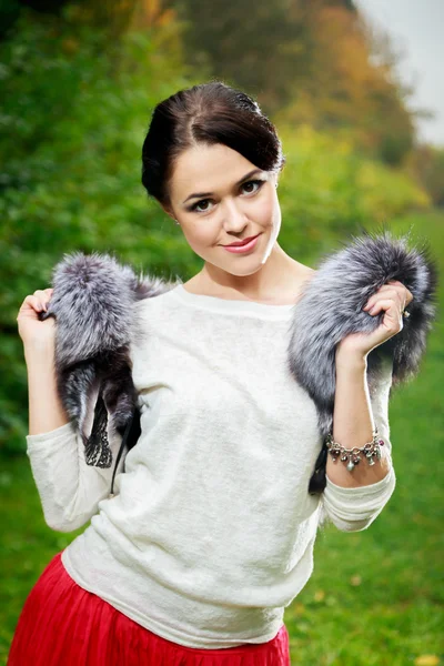 Beautiful girl in a red skirt and a fur vest in the forest — Stock Photo, Image