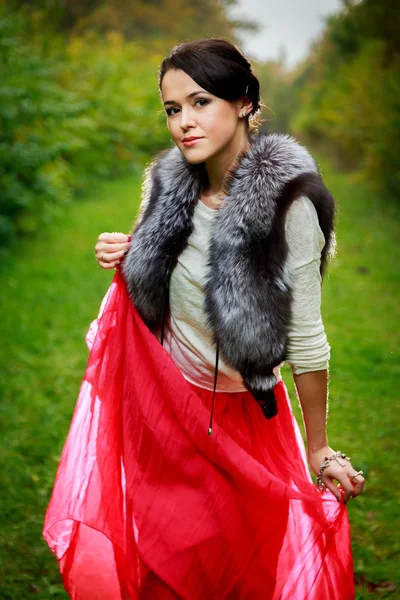 Bella ragazza in gonna rossa e gilet di pelliccia nella foresta — Foto Stock