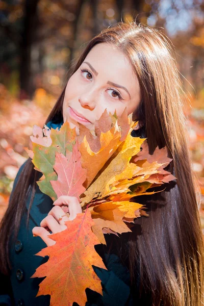 Девушка с кучей листьев в осеннем парке — стоковое фото