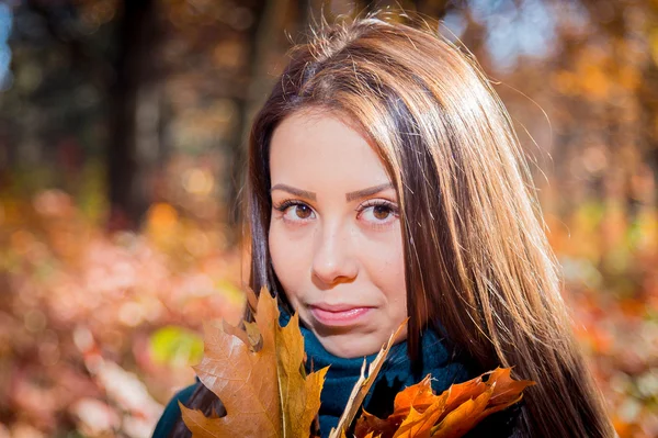 Dívka s hromadou listí v podzimním parku — Stock fotografie