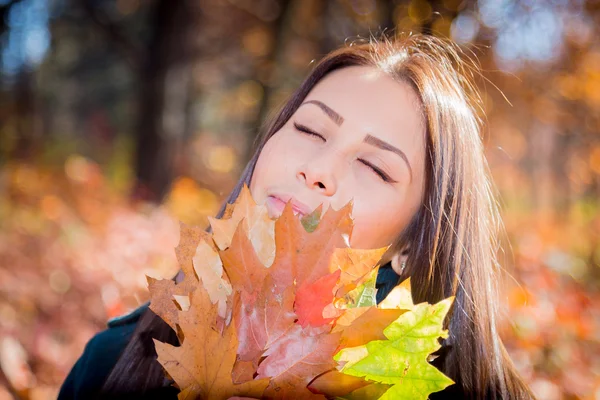 Snící dívka s hromadou listí v podzimním parku — Stock fotografie