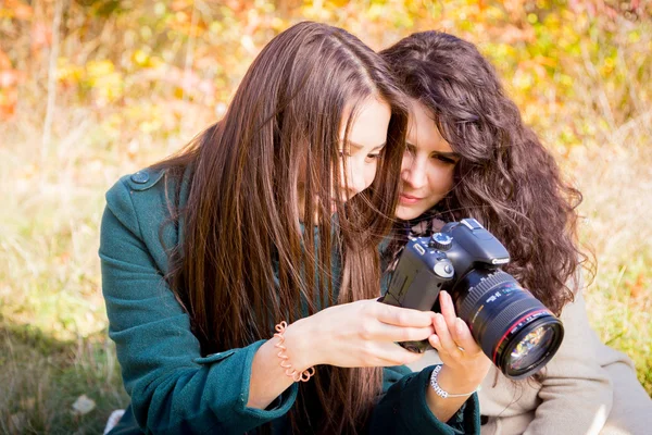 Κορίτσια ψάχνουν φωτογραφίες στην κάμερα στο πάρκο φθινόπωρο — Φωτογραφία Αρχείου