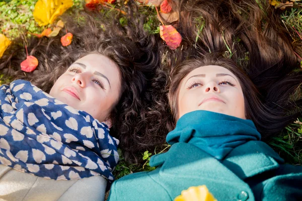 Flickor ligger på gräset i parken hösten — Stockfoto