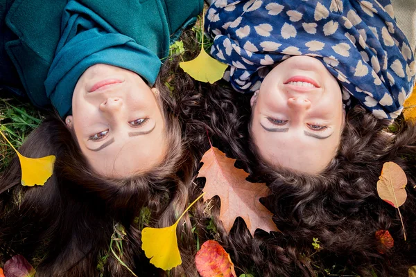 Girls lying on the grass in the autumn park — Stock Photo, Image