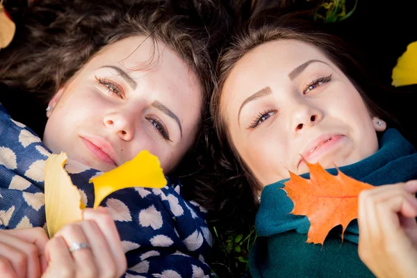 Meisjes liggen op het gras in de herfst park — Stockfoto