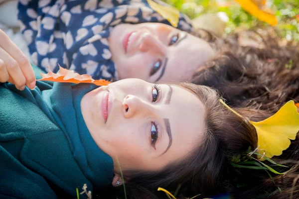 Girls lying on the grass in the autumn park — Stock Photo, Image