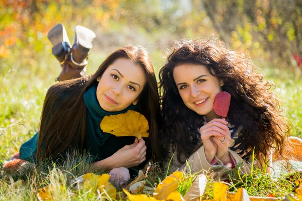 Girls lying on the grass in the autumn park — Stock Photo, Image