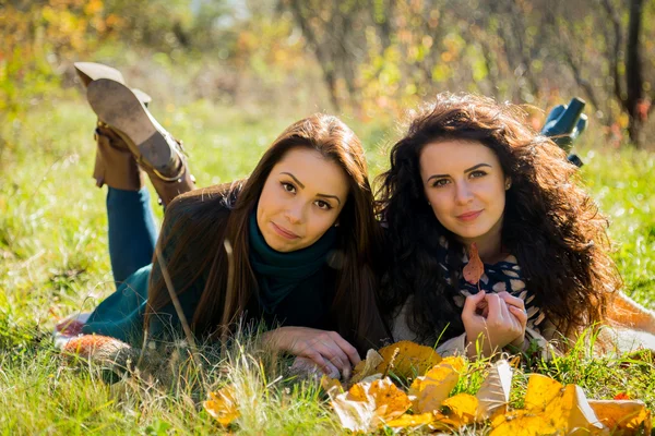 Girls lying on the grass in the autumn park — Stock Photo, Image