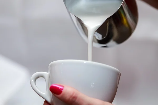 Mãos femininas derramando leite no copo — Fotografia de Stock