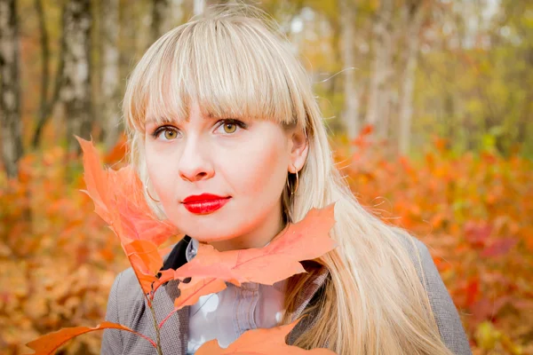 Pretty blonde girl holding autumn leaf — Stock Photo, Image