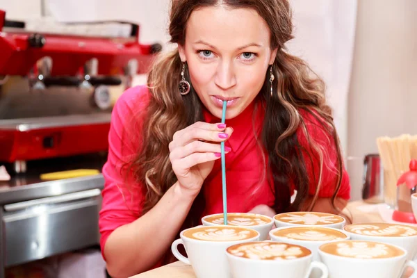 Žena pije cappuccino v kavárně s trubičkou — Stock fotografie