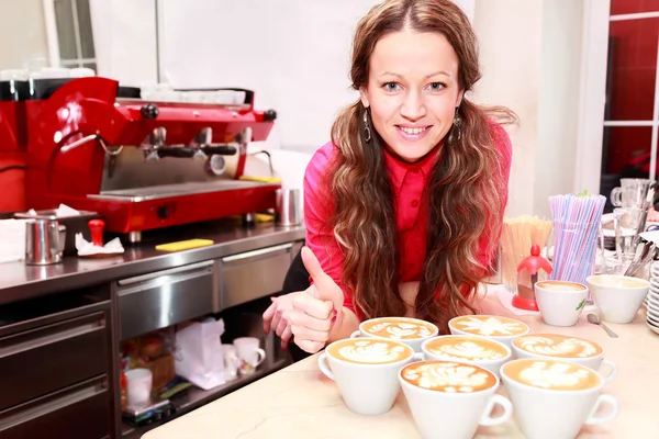 Mulher com sete xícaras de cappuccino mostrando gesto de trombo — Fotografia de Stock