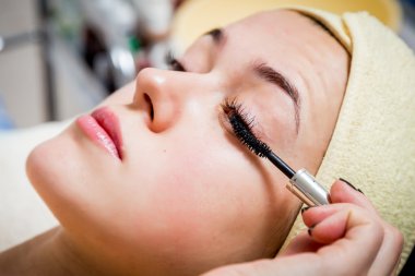 Makyöz, genç bir kadının profesyonel makyajını yapıyor.